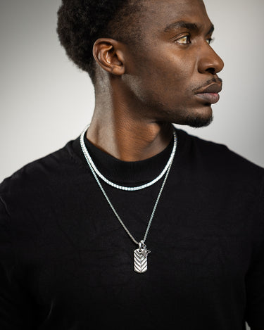 Man met luxe heren sieraden, waaronder de Shadow Arrow Zilverkleurig Ketting en een elegante halsketting.