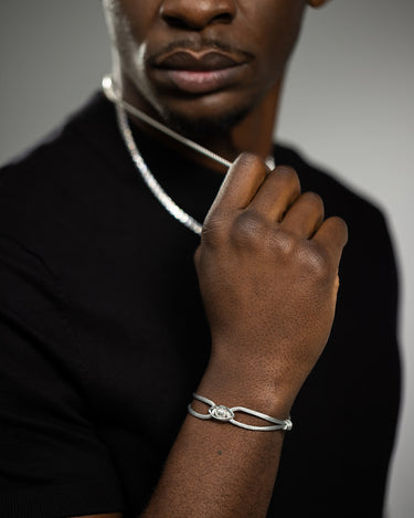 Emerald Guardian Grijs Armband Zilver op de hand van een man met een zilveren ketting, luxe heren sieraden.