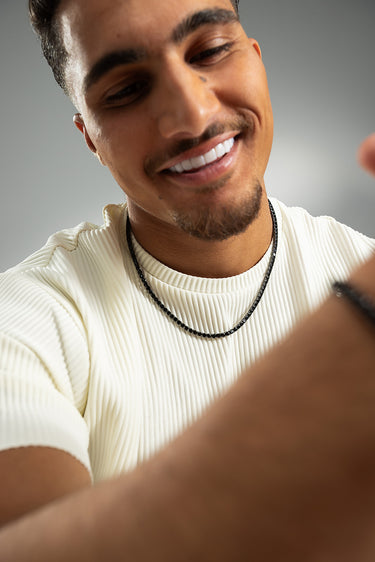 Man met een Crystal Embrace Zwart Tennis Ketting, die zijn sprankelende energie en helderheid uitstraalt.