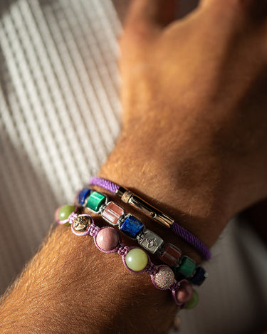 Armband met verschillende kleuren en materialen, gedragen op een hand, elegant en speels ontwerp.