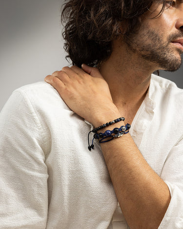 Man draagt een donkerblauwe armband met handgemaakte sieraden en luxe heren sieraden.