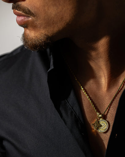Close-up van een man die een handgemaakte gouden ketting draagt met de RoanRoss logo